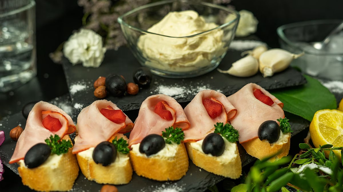 Close-up of ham and olive canapés with creamy dressing, perfect for elegant gatherings.
